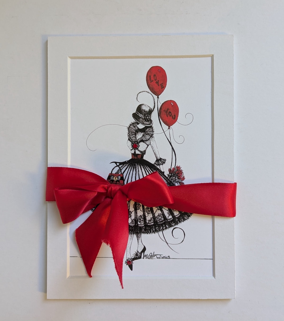 5x7 matted print with black and white illustration of MeowCleeva® holding red balloons, tied with a red double satin ribbon and bow. 