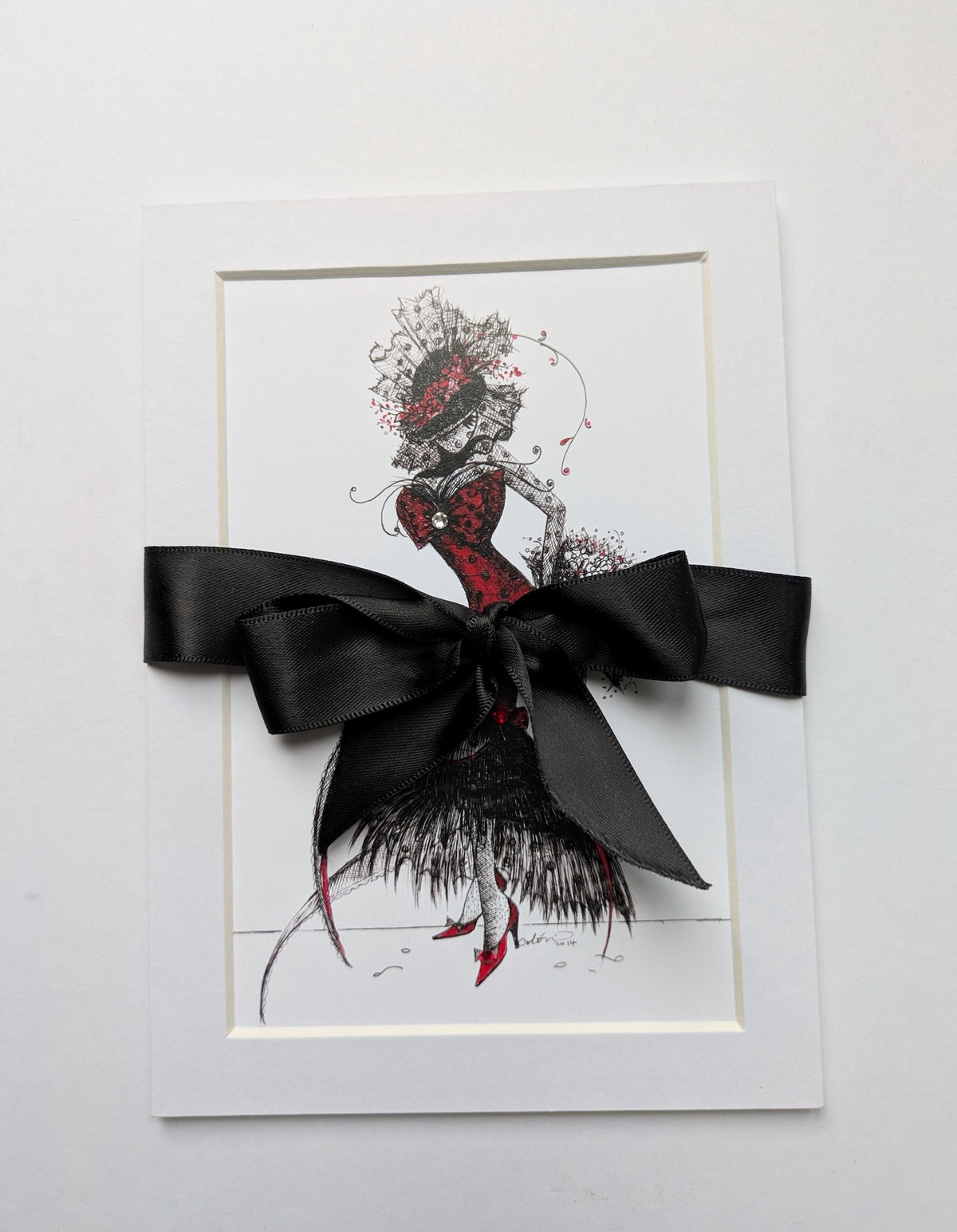 5x7" print featuring a whimsical illustration of the character MeowCleeva in a red and black dress. packaged with a large black satin ribbon bow across the center. By artist Martha Colón