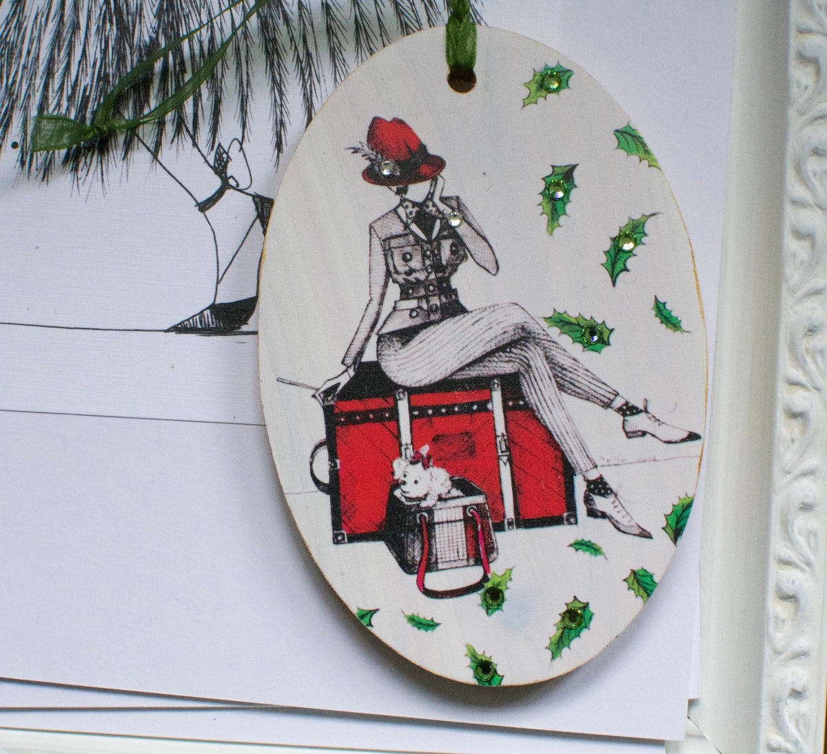 Hand painted wood ornament featuring MeowCleeva® seated on her red trunk with her little dog, adorned with Swarovski crystals. Holly border. One of a kind. $125.